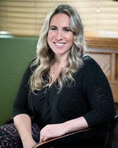 A woman sitting in front of a wooden desk.
