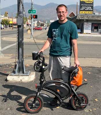 A man standing next to a small bike.