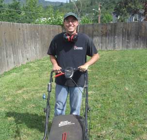 A man in black shirt holding a lawn mower.