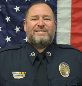 Board Member Doni Standing in front of flag wearing police uniform