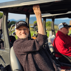 A man sitting in a golf cart smiling
