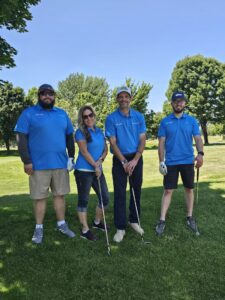 Four golfers posing on a sunny course.