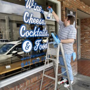 Man on ladder cleaning business window