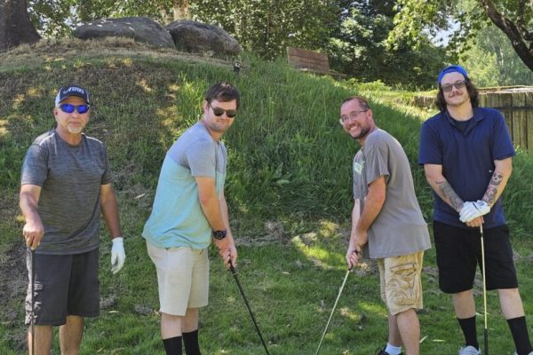 Four men posing on a golf course.