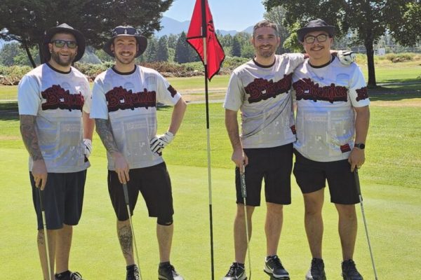 Four men posing on a golf course.