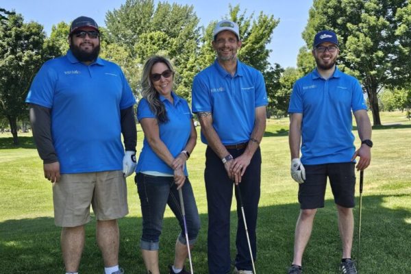 Four golfers posing on a sunny course.