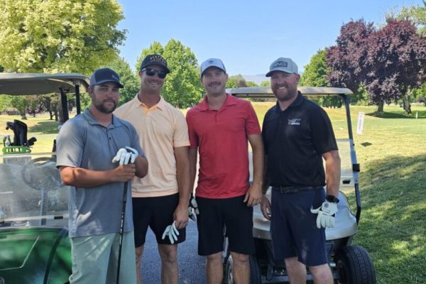 Four men posing on a golf course.
