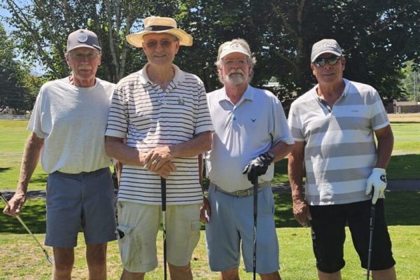 Four men posing on a golf course.