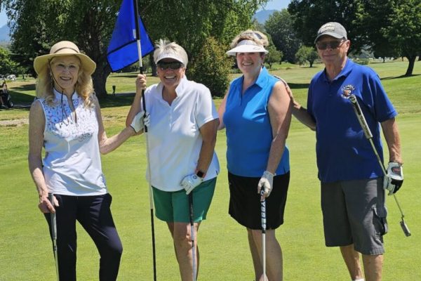 Four people posing on a golf course.