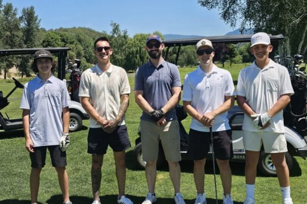 Five golfers posing on a sunny course.
