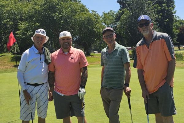 Four men posing on a golf course.